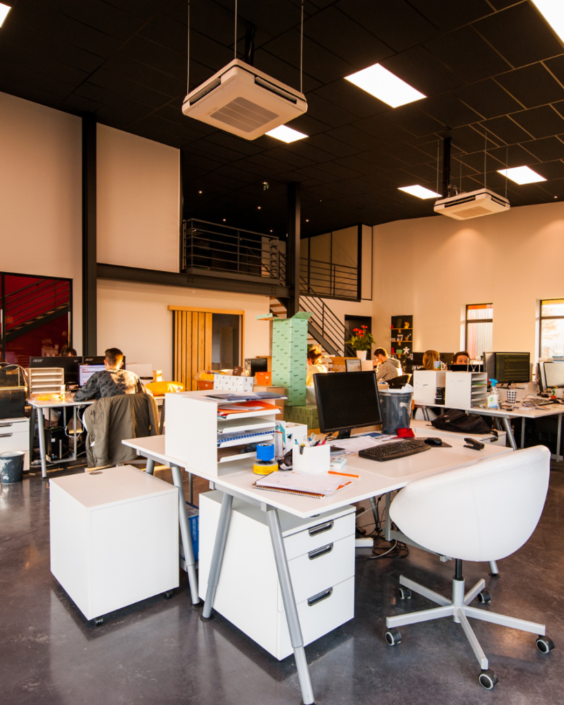 People Sitting on Desks Besides their Desks in an Office